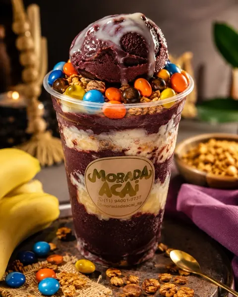 Copo de açaí cremoso com banana, granola e confeitos coloridos